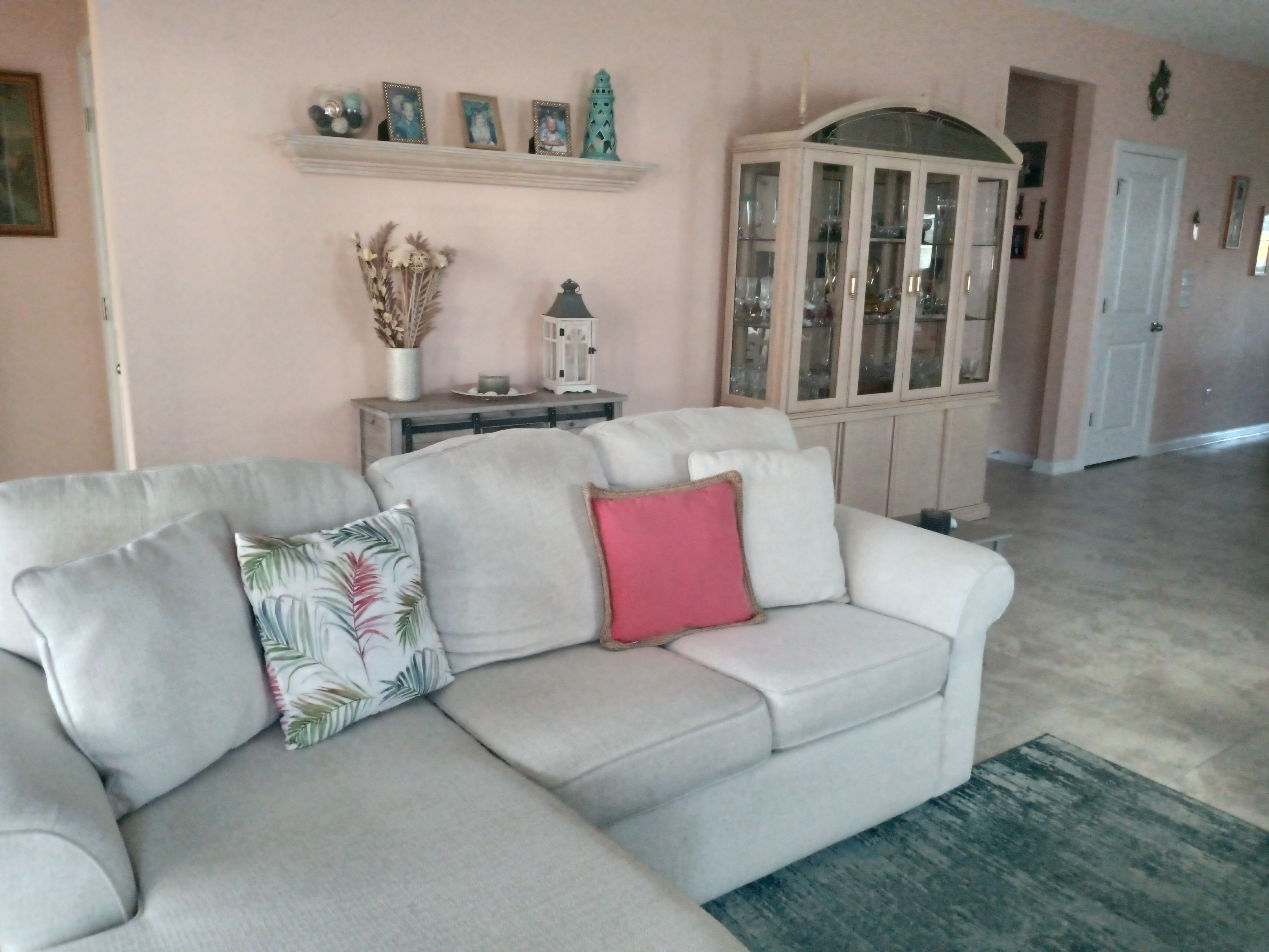 Living room with sectional sofa, china cabinet, and pink walls