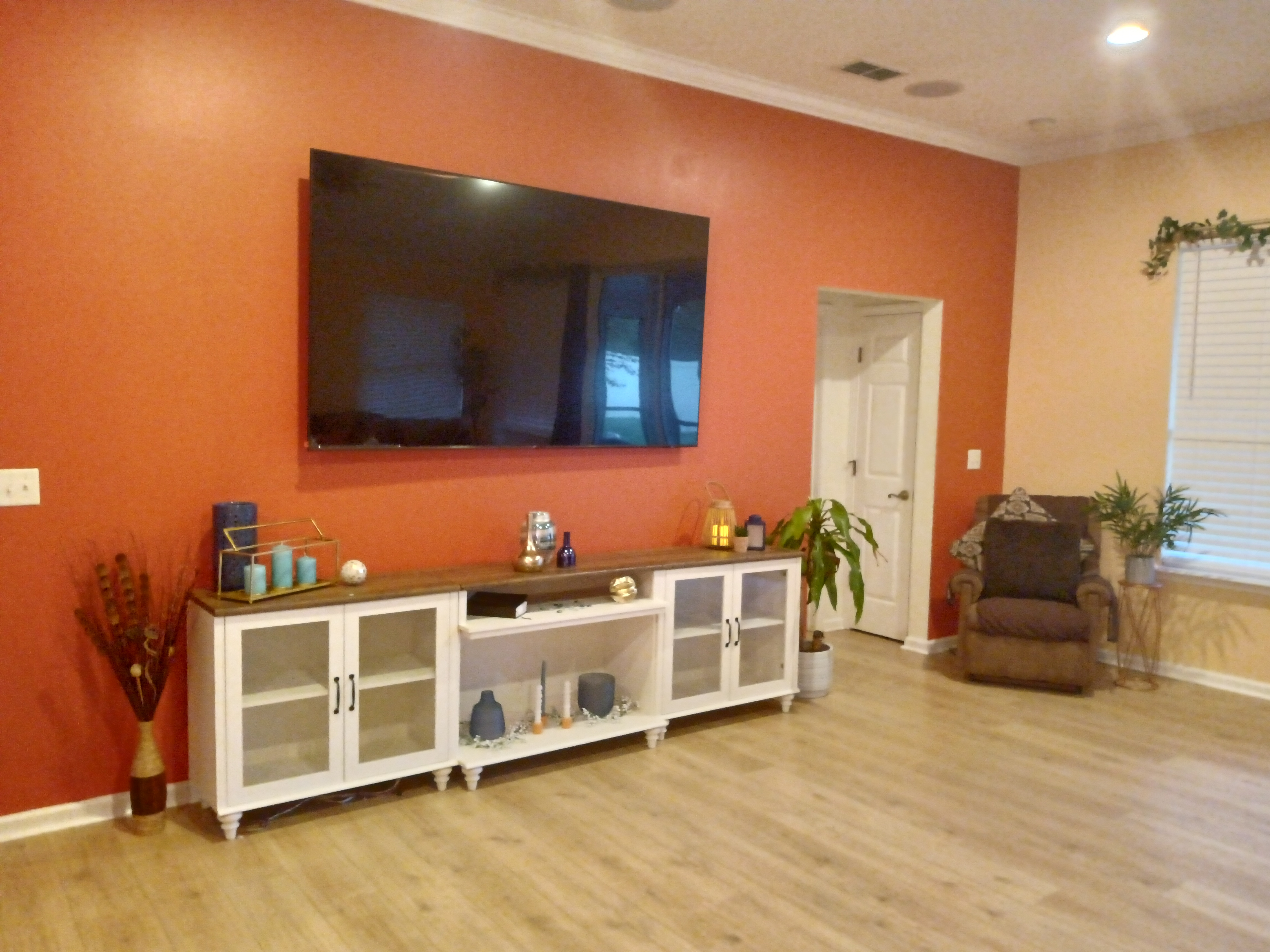 Living room with bold orange accent wall and media console