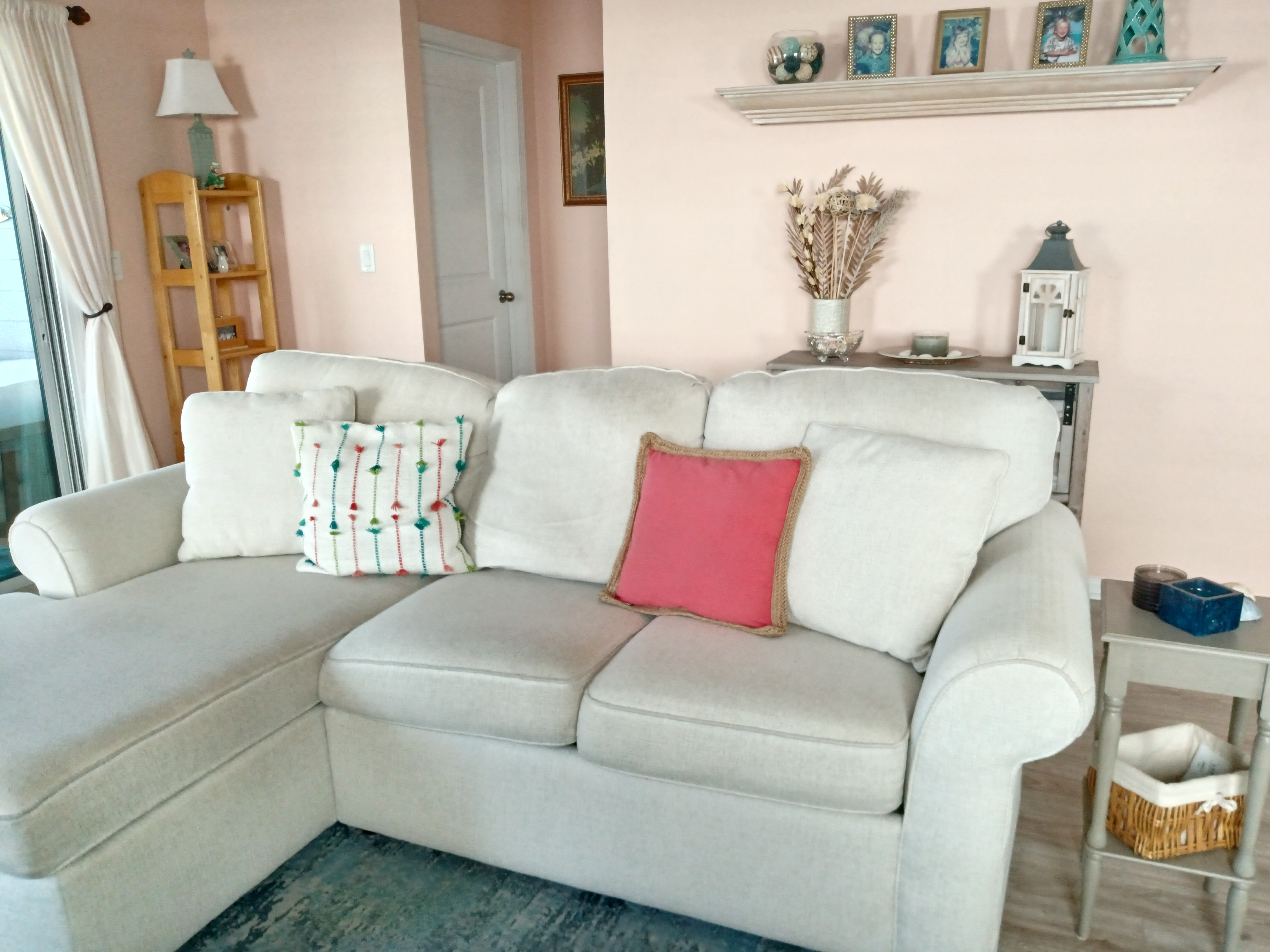 Living room sofa with pink accent pillow and shelf display